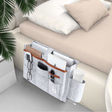 Grey bedside felt storage bag hanging from a bed, ideal for organizing books, gadgets, and more. Shopway.