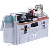 Grey felt bedside storage bag with multiple pockets for organizing essentials like magazines, gadgets, and toys. Available at Shopway.